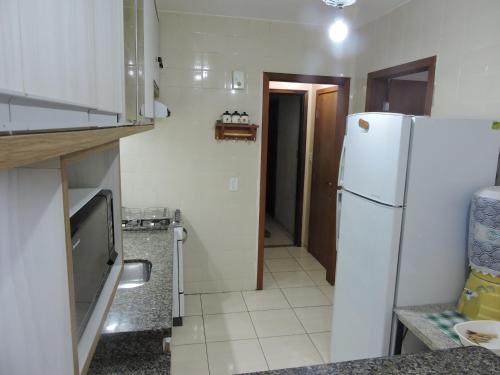 a kitchen with a white refrigerator and a hallway at Apto 2 quartos no centro de Bombinhas, 130 metros praia in Bombinhas