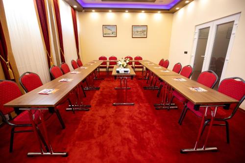 a conference room with wooden tables and red chairs at Boutique Hotel Golden Star in Tuzla