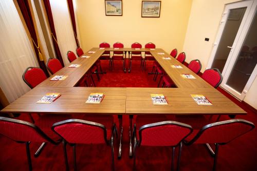 a conference room with a long table and red chairs at Boutique Hotel Golden Star in Tuzla