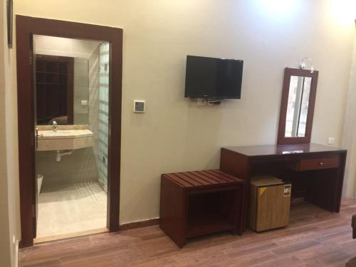 uma casa de banho com um espelho e um lavatório e uma televisão em Grand Palace Hotel no Cairo