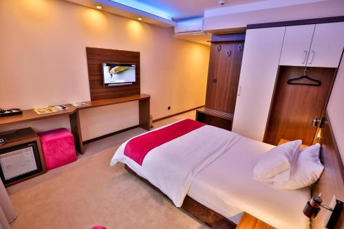 a bedroom with a large white bed and a tv at Boutique Hotel Golden Star in Tuzla