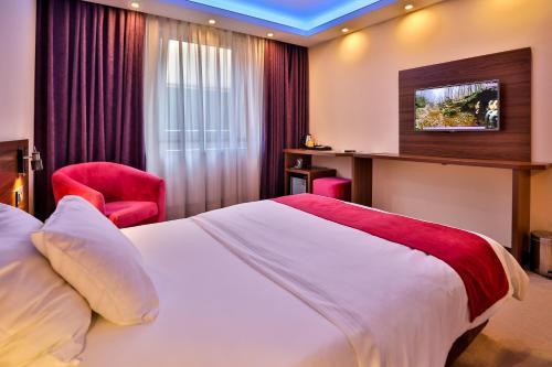 a hotel room with a bed and a red chair at Boutique Hotel Golden Star in Tuzla