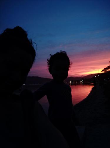 a silhouette of a woman and a child at sunset at Joaquina 433 - Pousada Floripa in Florianópolis