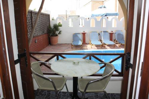 einen Tisch und Stühle auf einem Balkon mit Pool in der Unterkunft Pension Stella in Karterados