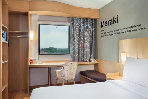 a bedroom with a desk with a computer and a window at ibis Pontianak City Center in Pontianak
