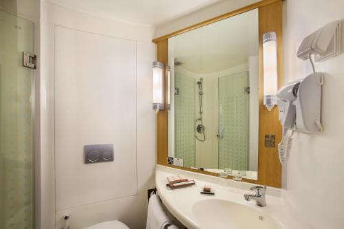 La salle de bains est pourvue d'un lavabo, de toilettes et d'un miroir. dans l'établissement ibis Pontianak City Center, à Pontianak