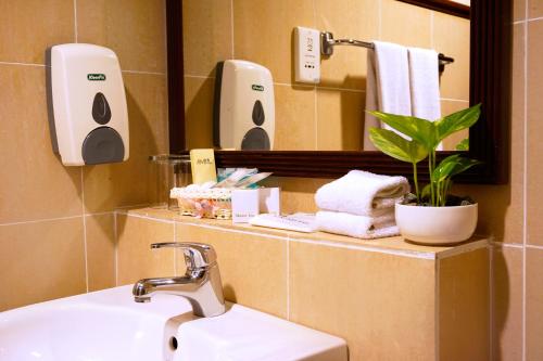 uma casa de banho com lavatório, espelho e toalhas em Kudat Golf & Marina Resort em Kudat