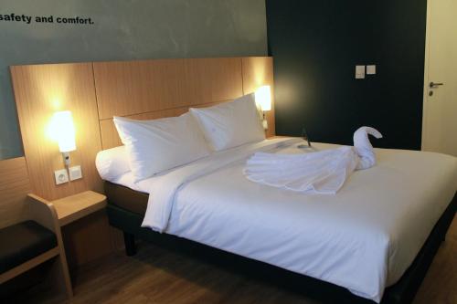 a white bed with a swan on top of it at ibis Pontianak City Center in Pontianak