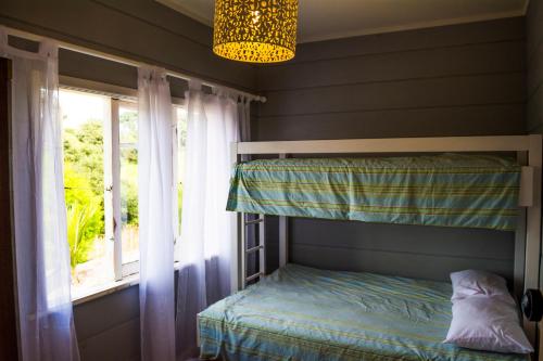 a bedroom with a bunk bed and a window at Freshwaterfarm Cottages - Muriwai in Waimauku