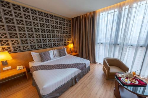 a hotel room with a large bed and a chair at Vivatel Kuala Lumpur in Kuala Lumpur