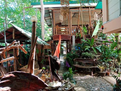 a house with a bunch of plants and an umbrella at Victoria Guest House and Cottages in Puerto Princesa City