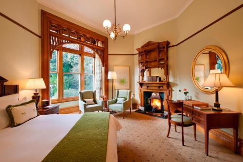 a bedroom with a bed and a desk and a fireplace at Otahuna Lodge in Christchurch