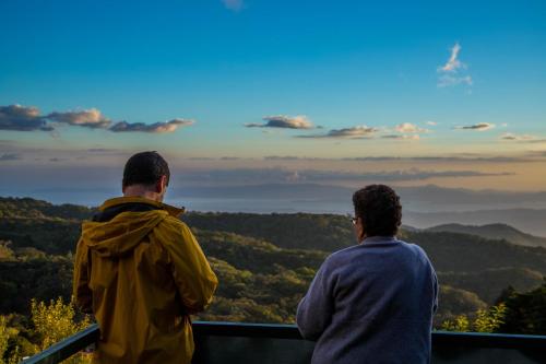 two men standing on top of a viewing tower looking out over the mountains at Los Pinos Cabins & Reserve in Monteverde Costa Rica