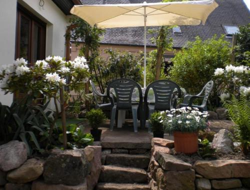 a patio with two chairs and an umbrella and flowers at Gite Le Mandlé in Riquewihr