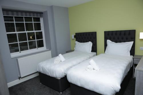 two beds in a room with a window at The Spring Bank APARTHOTEL in Preston