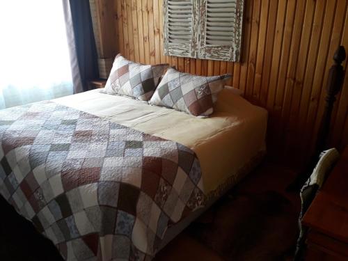 Bett mit einer Decke und Kissen im Zimmer in der Unterkunft Hostal Arce Marrón in Limache
