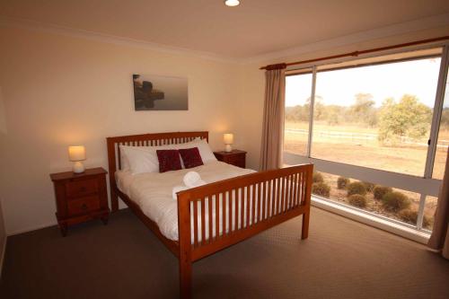 a bedroom with a bed and a large window at Verona Vineyard Cottage in Pokolbin