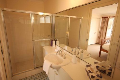 a bathroom with a shower and two sinks and a mirror at Verona Vineyard Cottage in Pokolbin