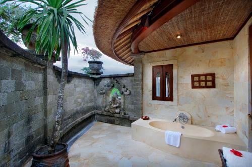 ein Badezimmer mit einer Badewanne und einer Palme in der Unterkunft Taman Wana Resort Palasari in Negara
