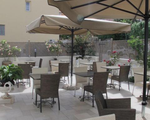 a patio area with tables, chairs and umbrellas at Hotel Le Havre Bleu in Beaulieu-sur-Mer