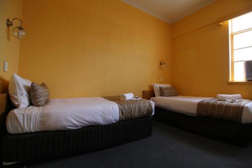 2 camas en una habitación con paredes amarillas en Beer Deluxe Albury, en Albury