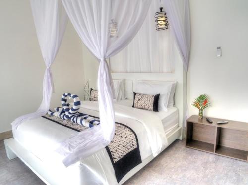 a bedroom with a white bed with a canopy at KyGunAya Villa in Gili Air