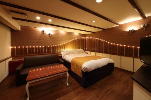 a bedroom with a bed and a couch and a television at Hotel Fine Garden Okayama I in Okayama