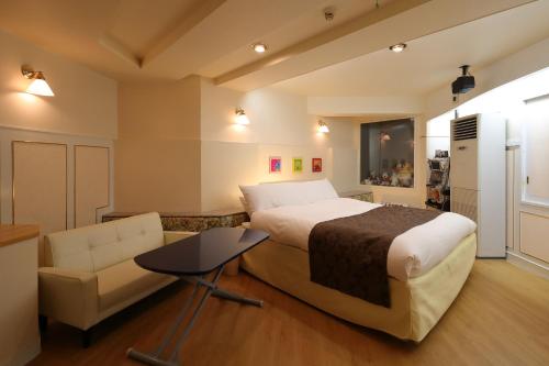une chambre avec un lit, un canapé et une chaise dans l'établissement Hotel Fine Garden Okayama I, à Okayama