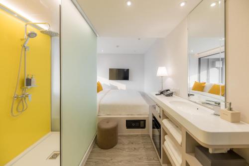 a bathroom with a bed and two sinks and a shower at Yello Rooms Hotel Victory Monument in Bangkok