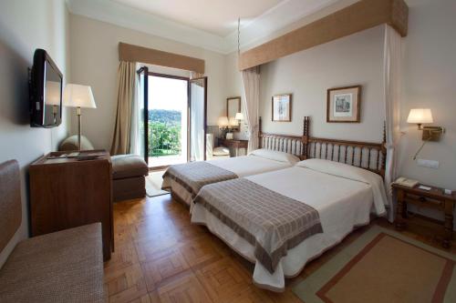 a bedroom with two beds and a large window at Parador de Teruel in Teruel
