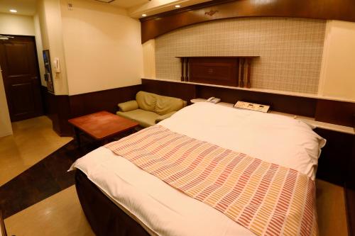 a hotel room with a bed and a chair at Hotel Fine Garden Kosei (Adult Only) in Konan