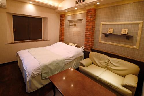 a room with a bed and a couch and a table at Hotel Fine Garden Kosei (Adult Only) in Konan