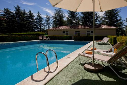a swimming pool with two chairs and an umbrella at Parador de Teruel in Teruel