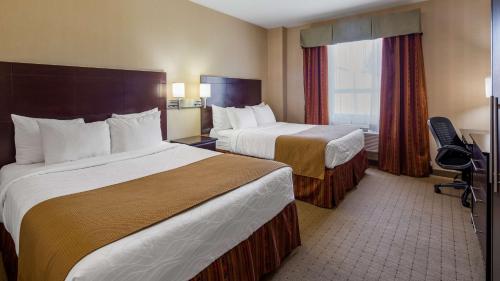 a hotel room with two beds and a window at Best Western Plus Bowmanville in Bowmanville