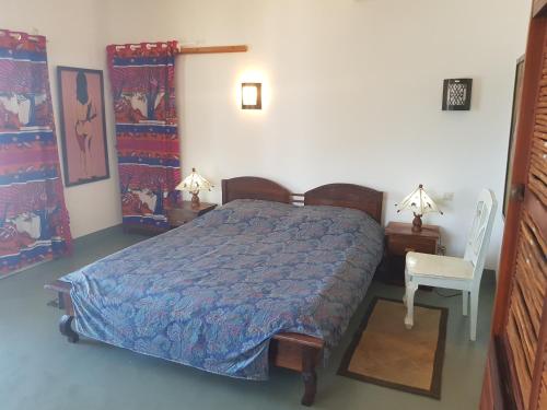 a bedroom with a bed and two tables and a chair at Villa océane in Tôlagnaro