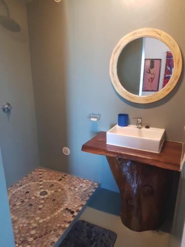 ein Bad mit einem Waschbecken und einem Spiegel in der Unterkunft Villa océane in Tôlagnaro