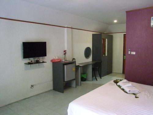 a bedroom with a bed and a desk with a television at Samui Green Hotel in Chaweng