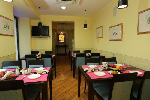 a dining room with tables and chairs and a television at Rigel Hotel in Catania