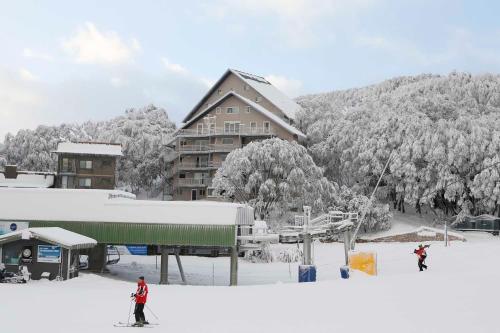 twee mensen skiën in de sneeuw voor een skihut bij Les Chalets 20 in Falls Creek