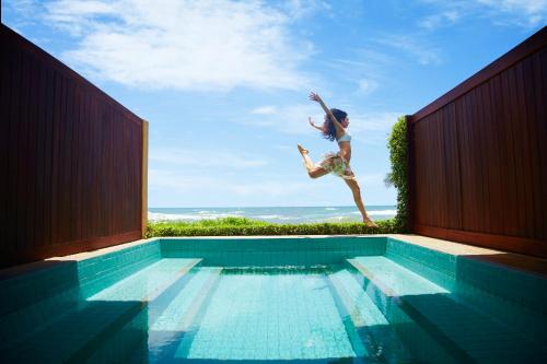 a woman jumping into a swimming pool at Jetwing Lighthouse, A Luxury Reserve in Galle