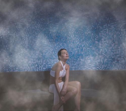 a woman sitting in front of a swimming pool at Jetwing Lighthouse, A Luxury Reserve in Galle