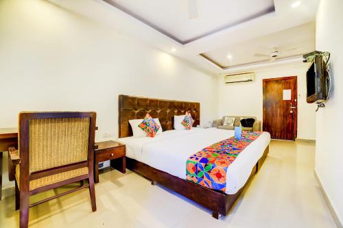 a bedroom with a bed and a chair and a television at Nitya Resort, Calangute in Calangute