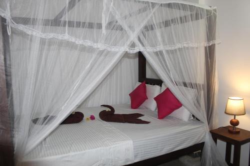 a bedroom with a white canopy bed with pink pillows at Sujee Villa in Unawatuna