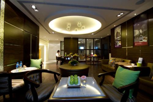 um lobby do hotel com uma mesa e cadeiras e uma pessoa ao fundo em Taichung Charming City Hotel em Taichung