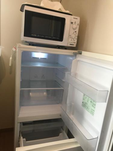 an empty refrigerator with a microwave on top of it at Weekly Harbourview Mansion Ginowan in Ginowan