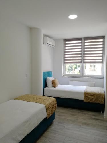 two beds in a room with white walls and windows at VIP Apartments in Sarajevo