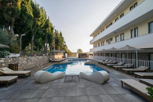 a hotel swimming pool with lounge chairs and a building at Sunny Days in Tigaki