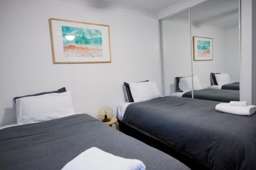 a bedroom with two beds and a mirror at FortyTwo - Oceanside Retreat Busselton in Busselton