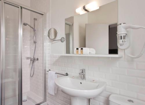 a white bathroom with a sink and a shower at Hôtel des Ecrivains in Paris