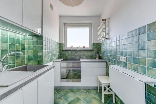 a kitchen with white cabinets and green tiles at Apartament z widokiem na morze in Sopot